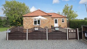 A brick house with a tiled roof, a white door, and a small window. - The New Build (Louth)