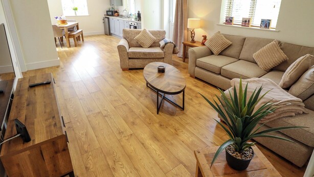 A spacious living area with a sofa set, a coffee table, and a dining table. - The New Build (Louth)