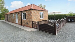A small brick building with a red-tiled roof, a gated entrance, and a gravel driveway. - The New Build (Louth)