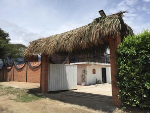 A house with a thatched roof, a brick exterior, and a gated entrance.