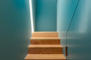 Una escalera con escalones de madera y una lámpara en la pared.