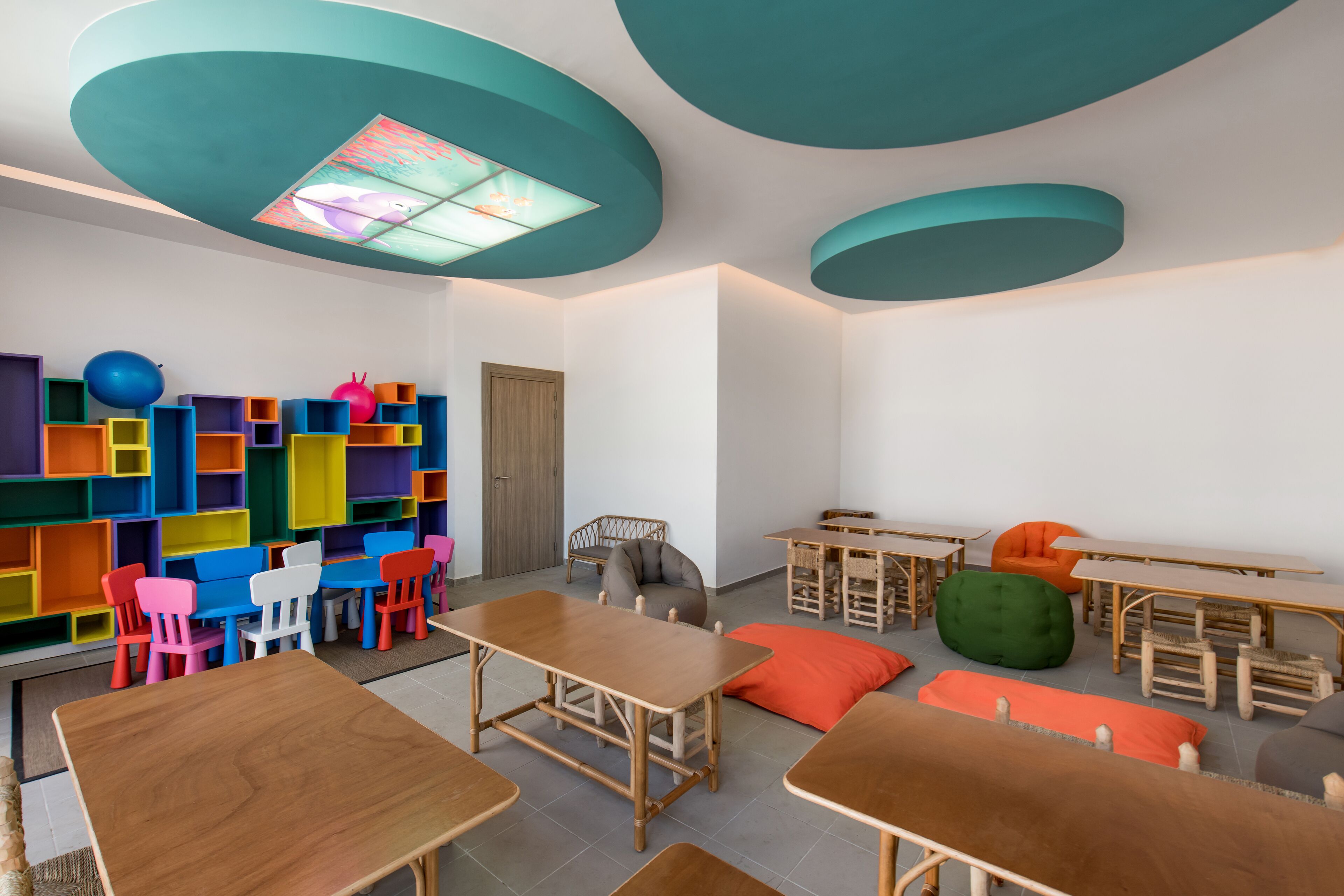 A classroom with colorful storage units, wooden tables, and chairs.