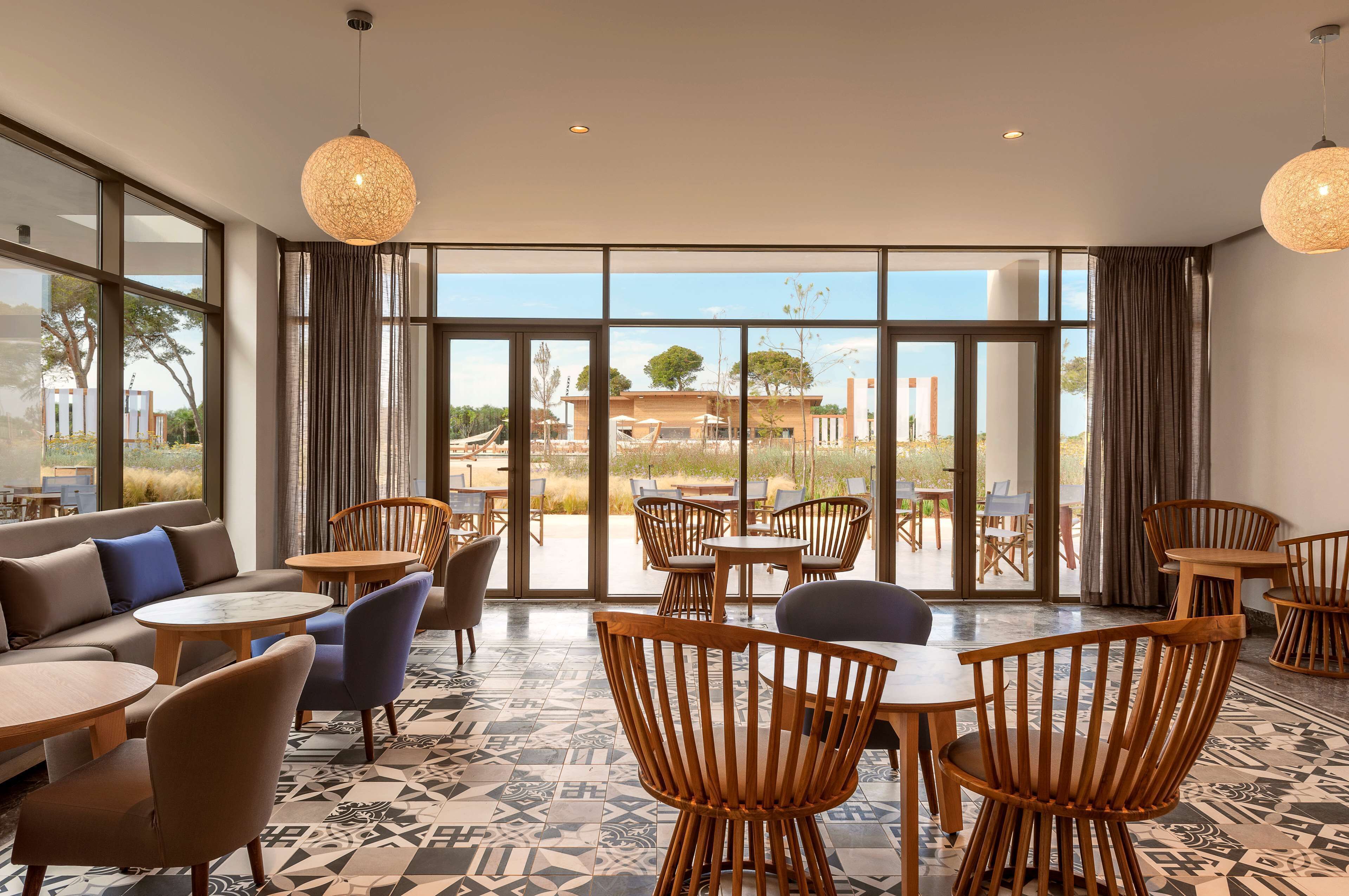 A spacious indoor area with large windows, wooden furniture, and a patterned floor.