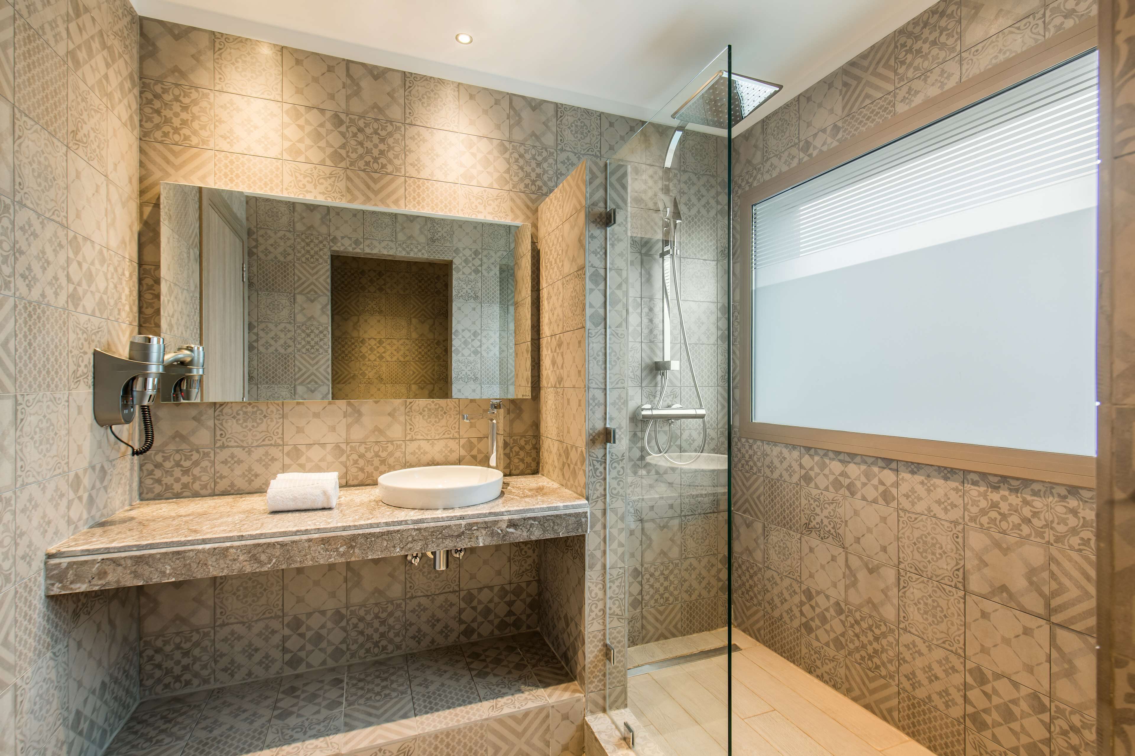 A modern bathroom with a glass-enclosed shower, a vanity with a sink, and a large mirror.