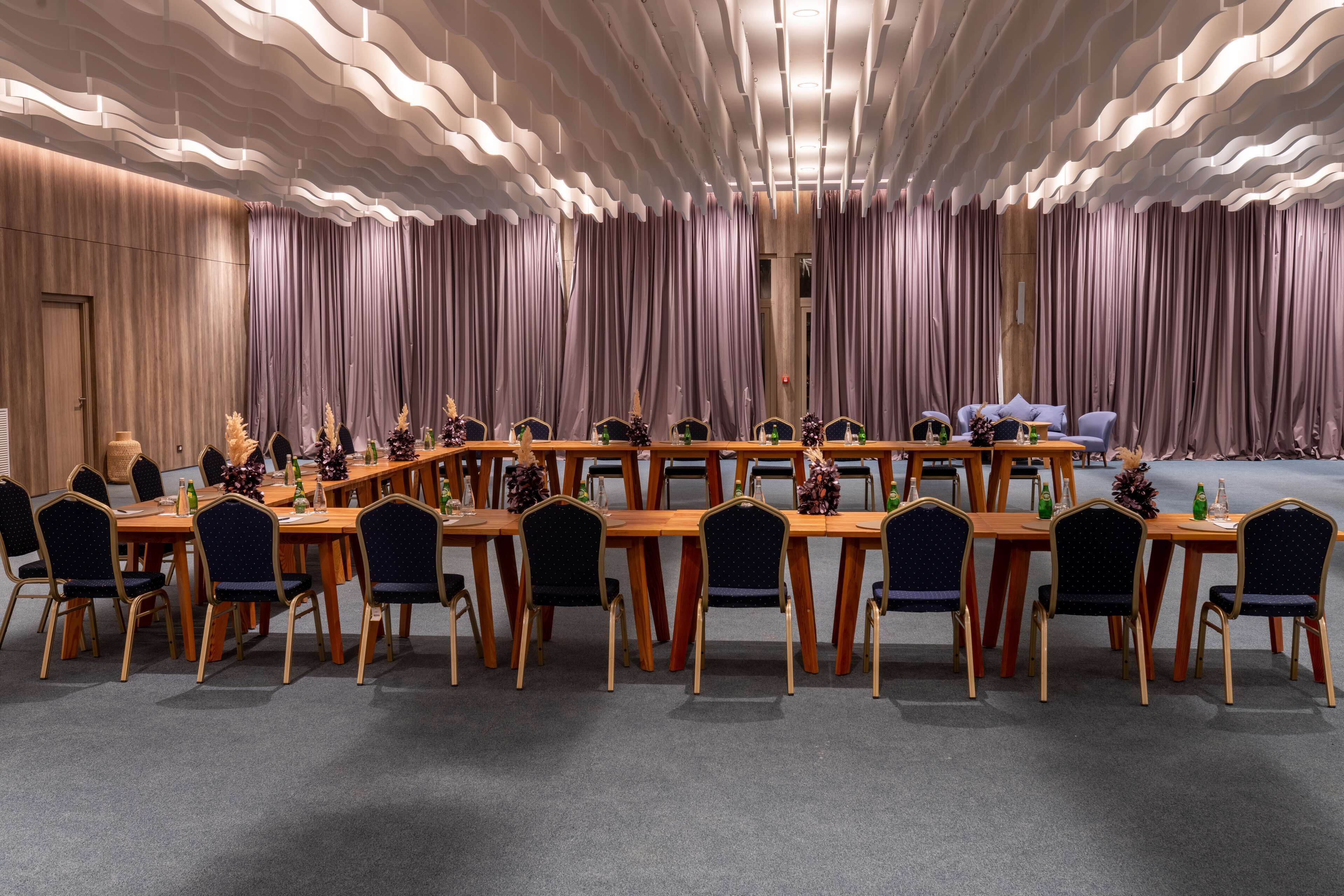 A conference room with a long table, chairs, and a stage.