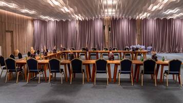 A conference room with a long table, chairs, and a stage.