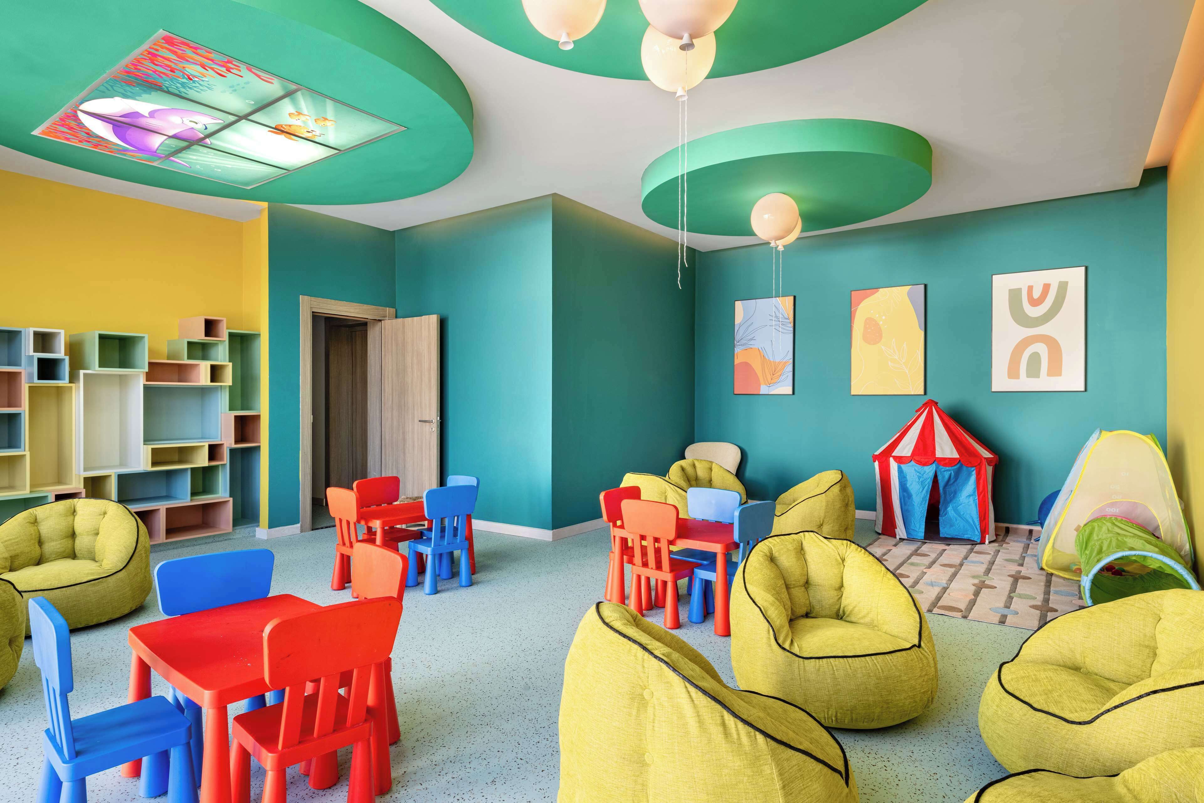 A children's playroom with colorful furniture, a playhouse, and a ceiling with a stained glass window.