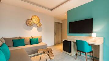Una sala de estar moderna con un sofá, cojines color turquesa, una mesa de centro de madera y un televisor montado en una pared color turquesa.