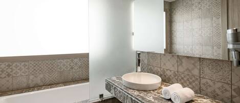 A modern bathroom with a bathtub, a round sink, and a large mirror.