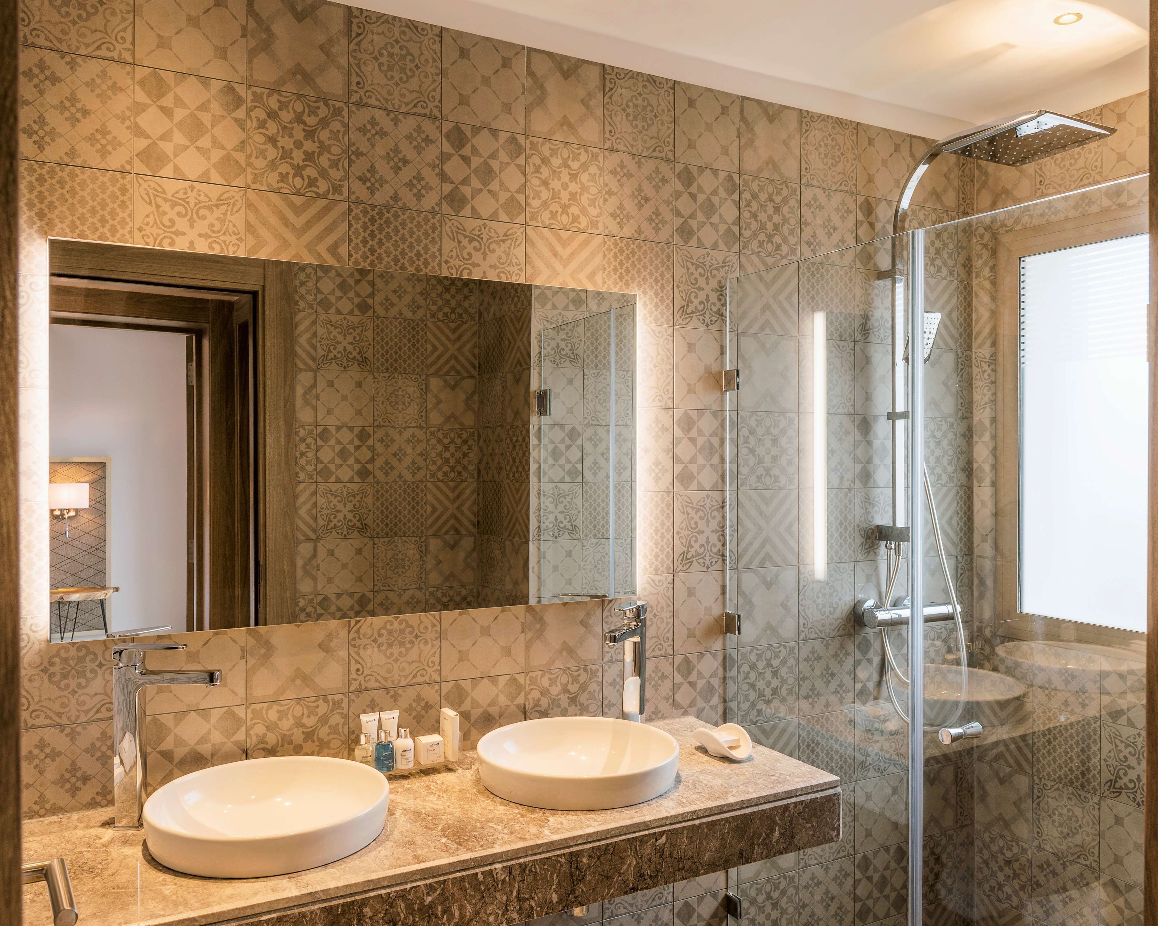 A bathroom with two sinks, a large mirror, and a glass-enclosed shower.