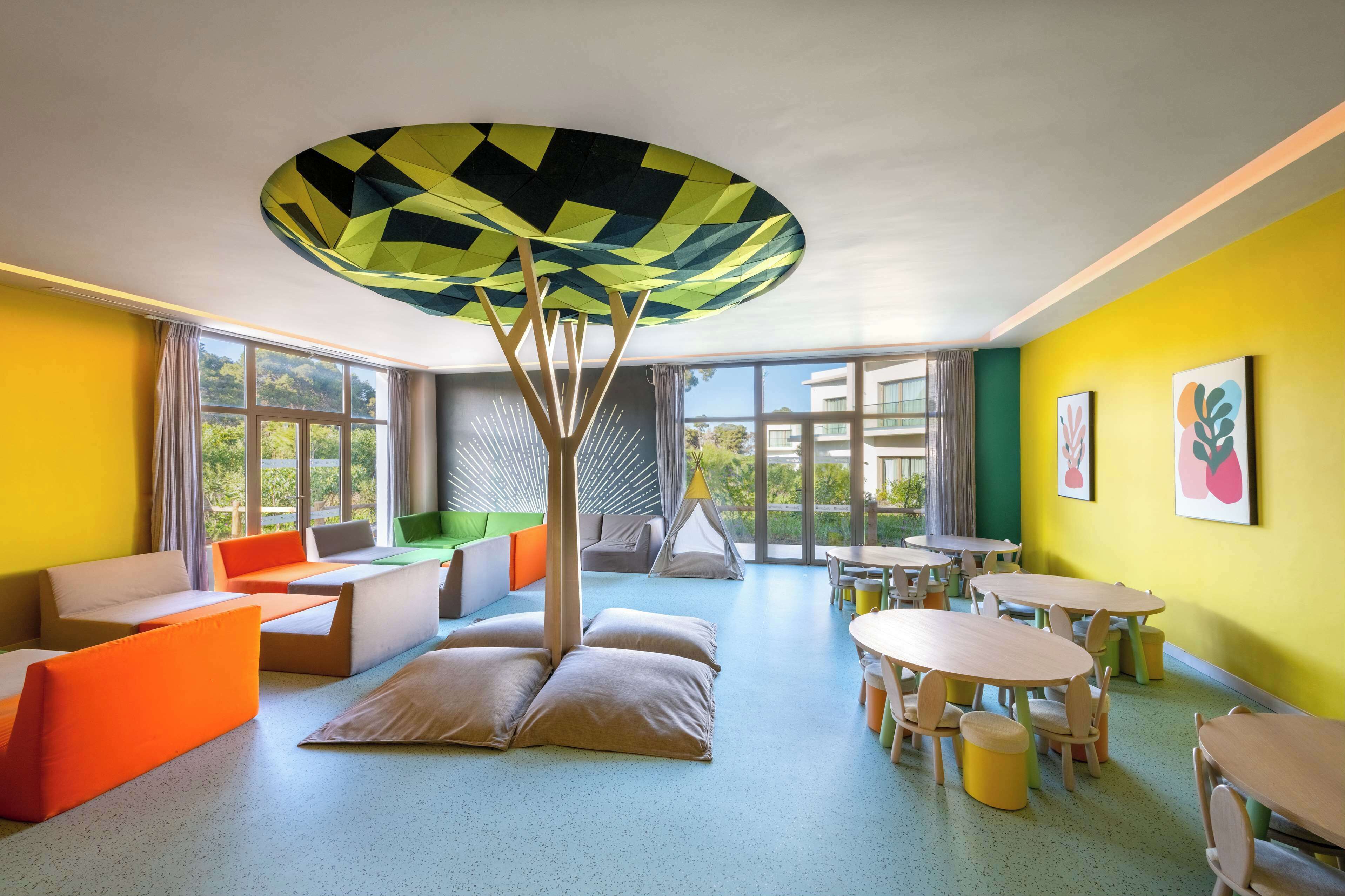 Une pièce aux couleurs vives, dotée d’un plafond au design original, de grandes fenêtres et de différents types de sièges.