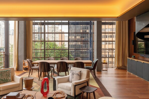 Una sala moderna con comedor, ventanas amplias y un televisor de pantalla plana.