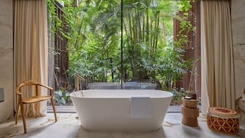 A bathroom with a freestanding bathtub, a wooden chair, and a small round table with a woven basket.