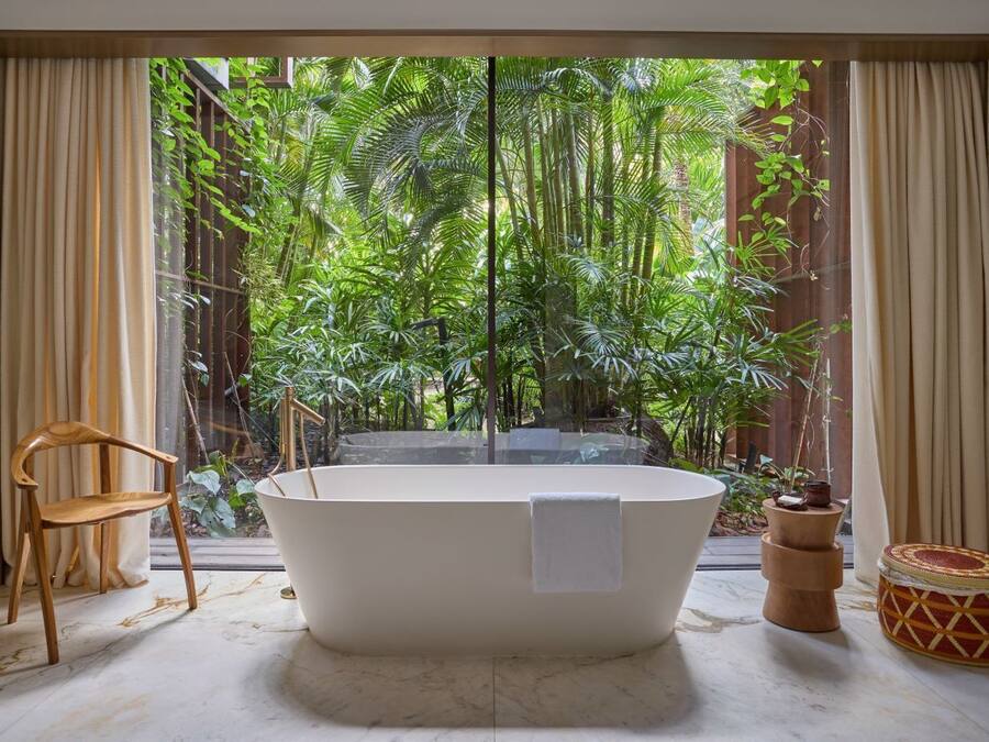 A bathroom with a freestanding bathtub, a wooden chair, and a small round table with a woven basket.