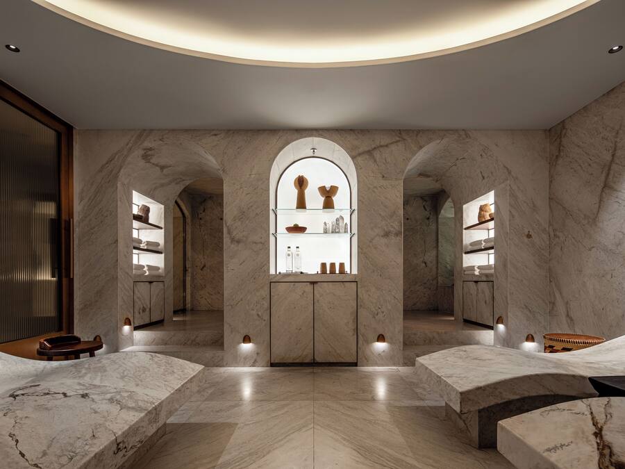 Un spa moderno con suelos de mármol, un llamativo arco central y dos zonas de estar.