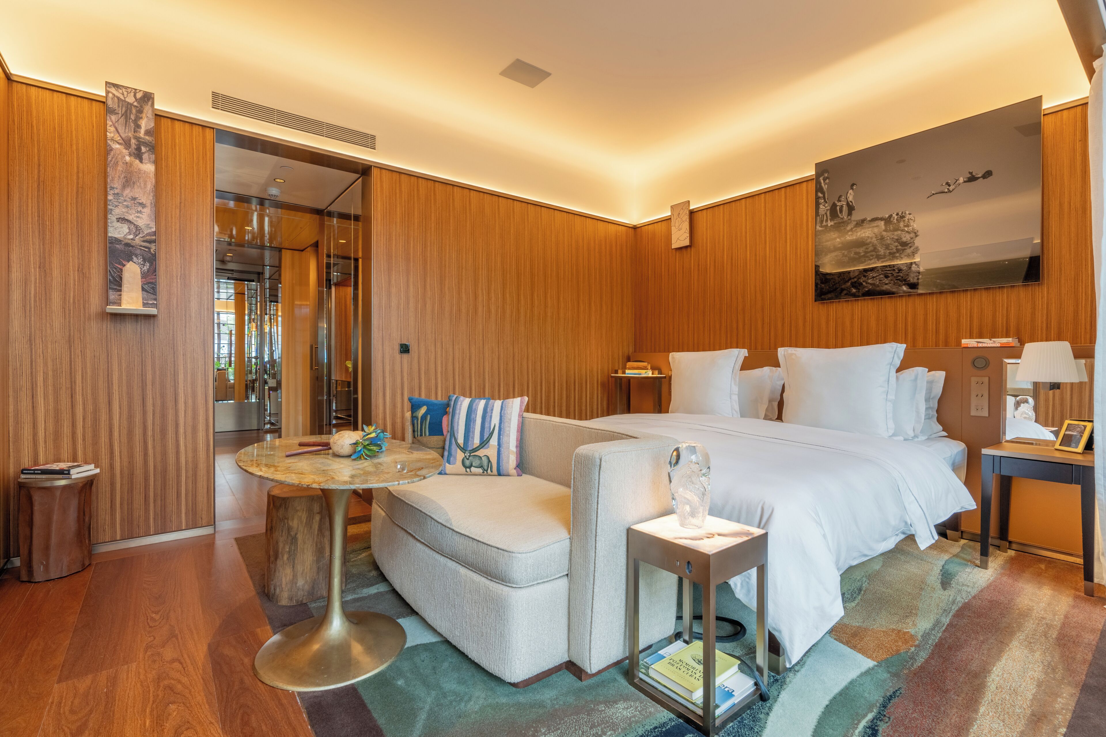 A hotel room with a bed, a sofa, a small table, and a nightstand.