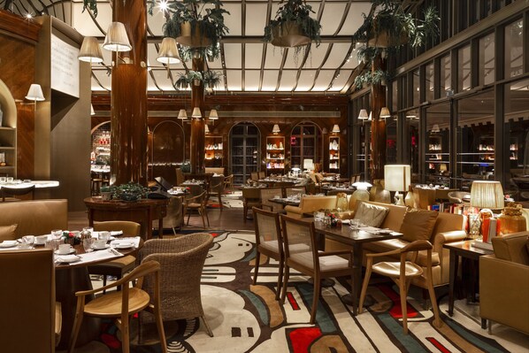 Un hall de hotel espacioso con varias zonas de estar, incluyendo un bar y mesas para comer.