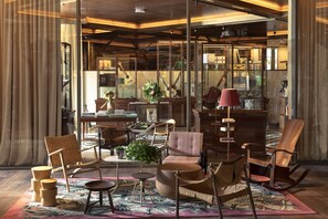 Une pièce spacieuse dotée d’une grande fenêtre, d’un plancher en bois et de différents types de sièges, notamment des chaises et un canapé.