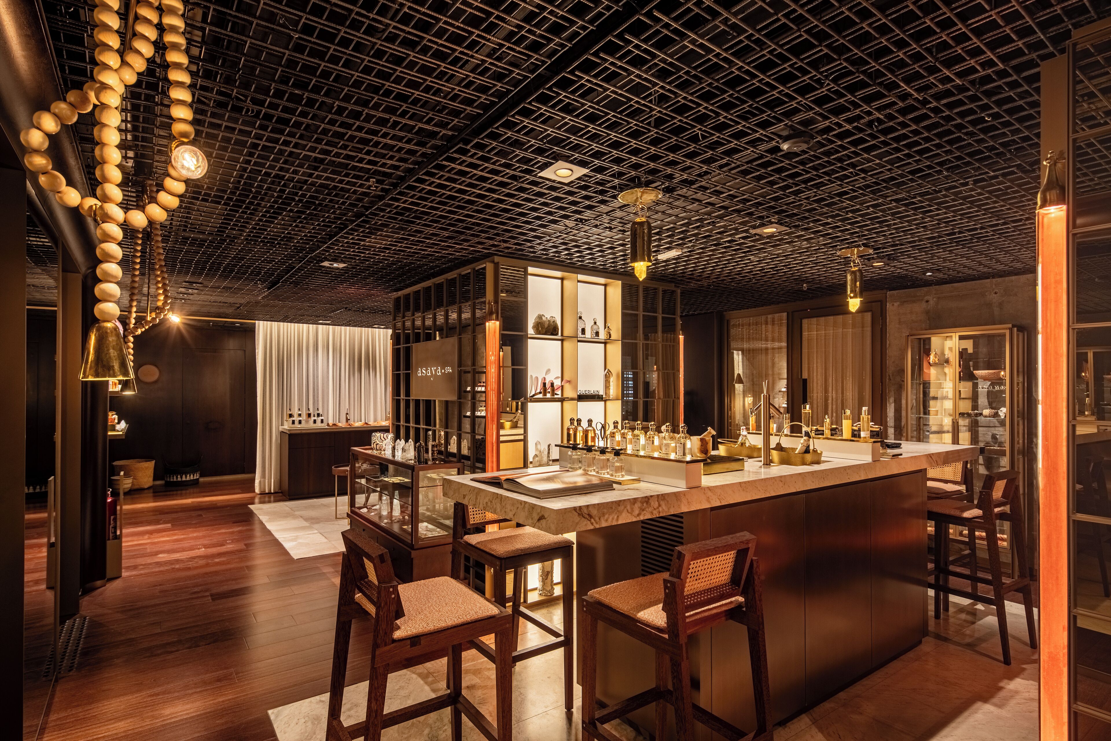 Zona de bar moderna amb una illa central, tamborets i un sostre amb dibuix de graella.