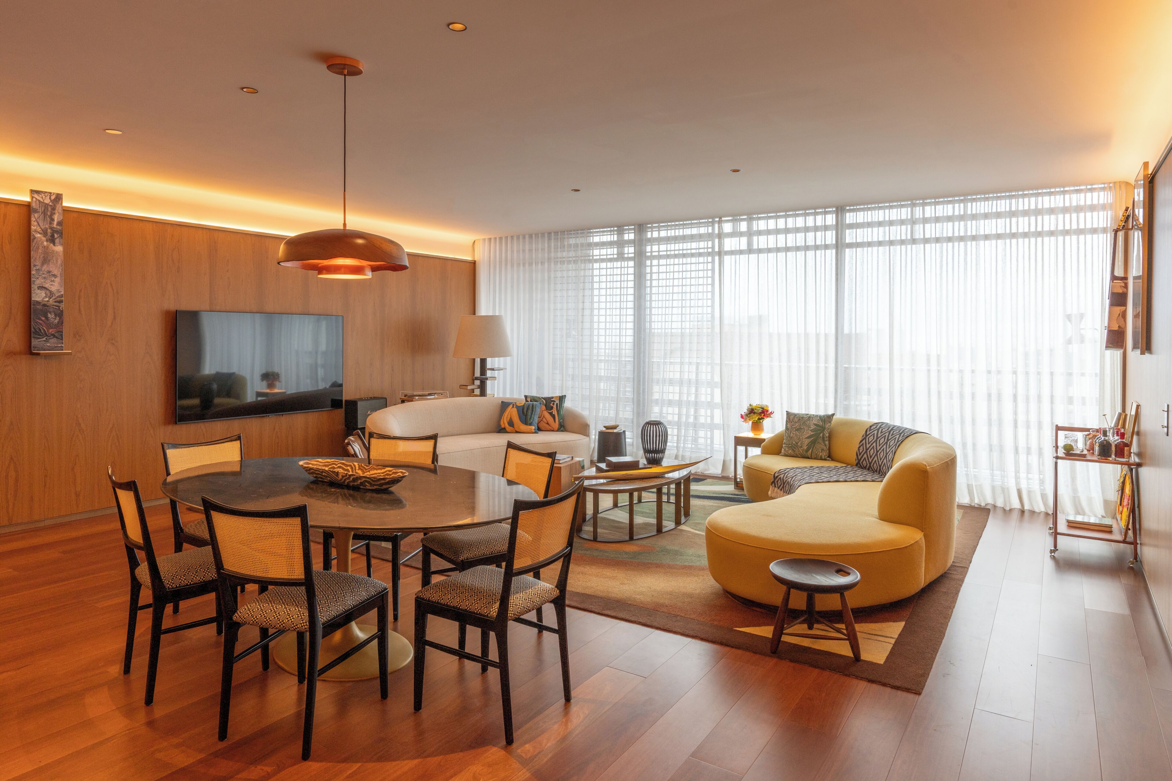 A modern living room with a dining area, a sofa, a coffee table, and a TV.