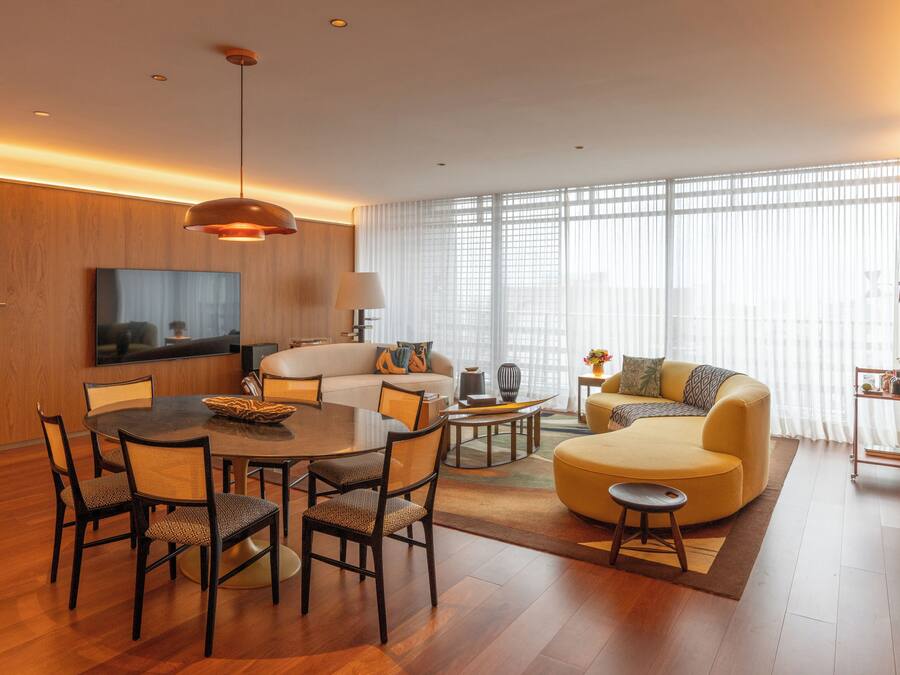 A modern living room with a dining area, a sofa, a coffee table, and a TV.