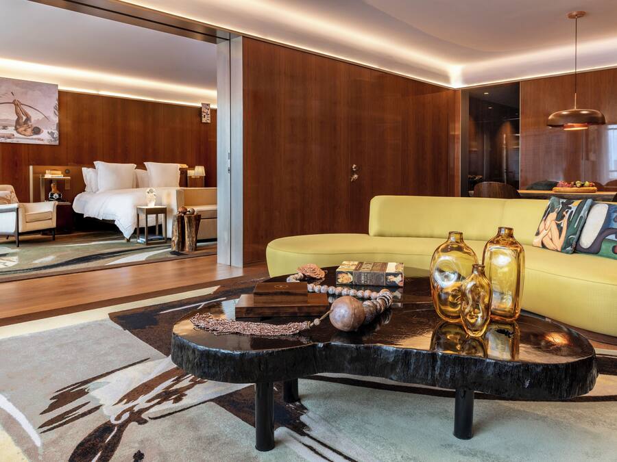 A modern living room with a yellow sofa, a black coffee table with decorative items, and a wooden floor.