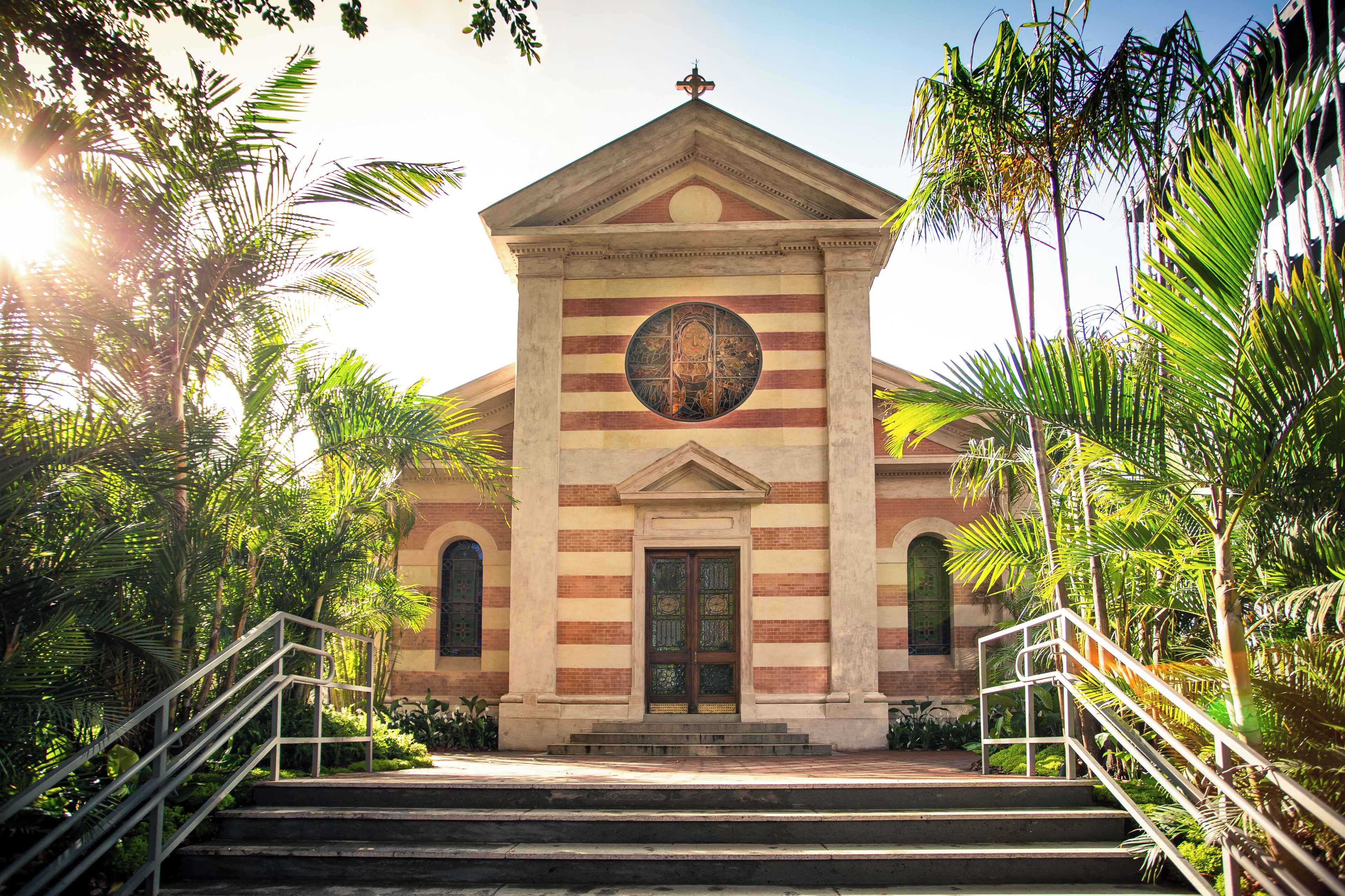 A building with a central dome, a staircase leading to the entrance, and surrounding greenery.