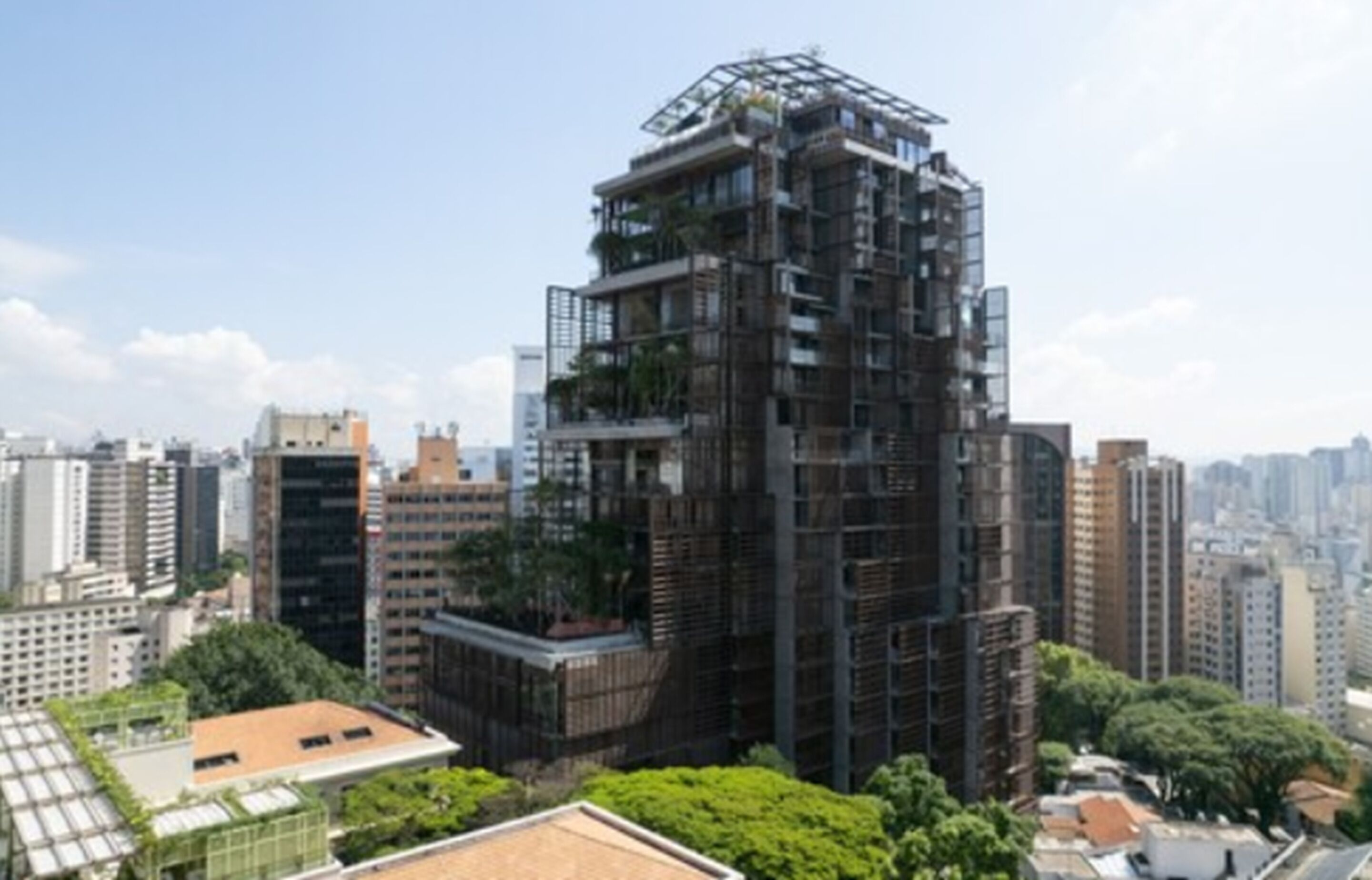 Un edificio de gran altura con varios balcones y un jardín en la azotea.