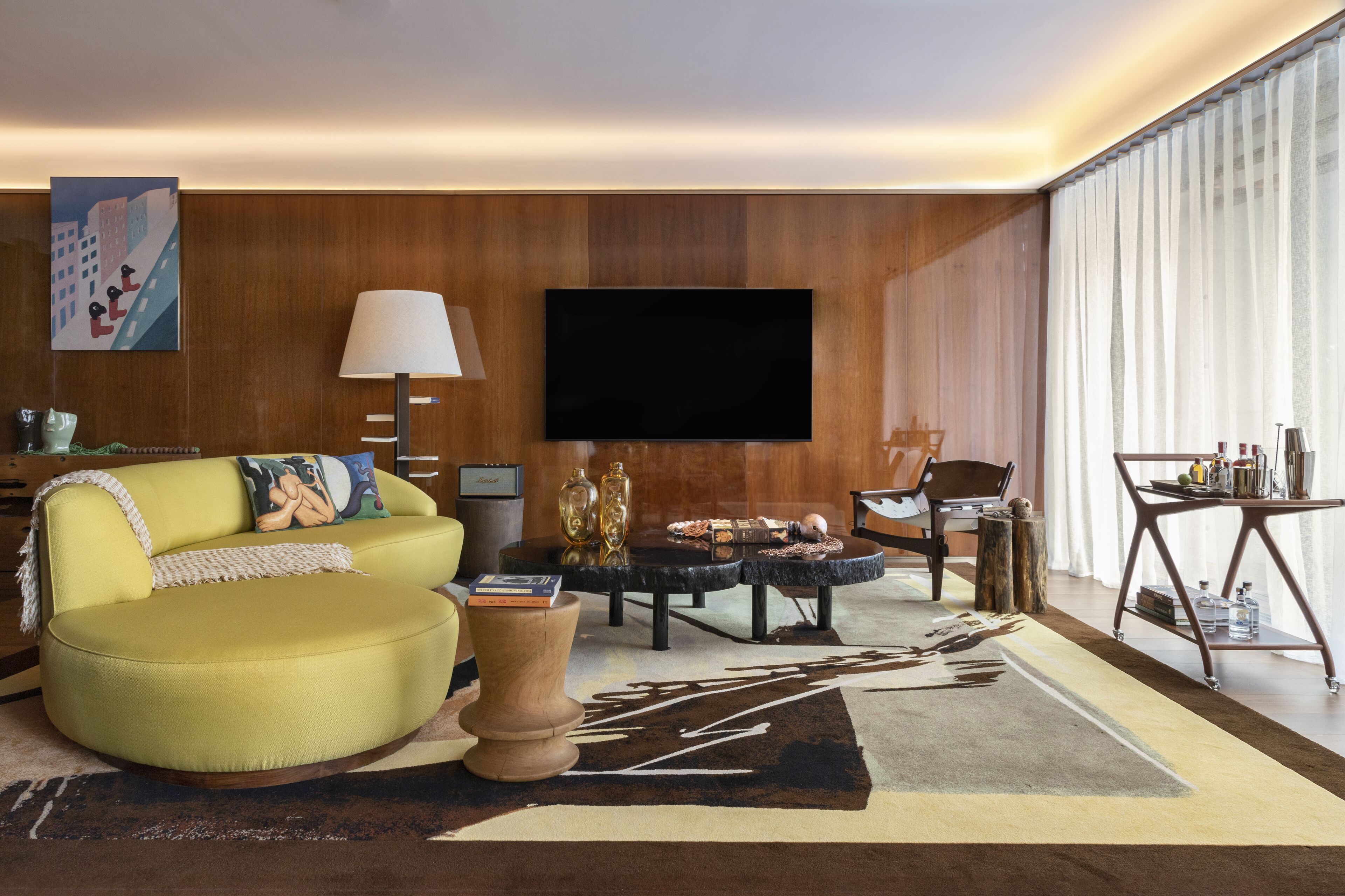 A modern living room with a sofa, coffee table, TV, and a view of the city through large windows.