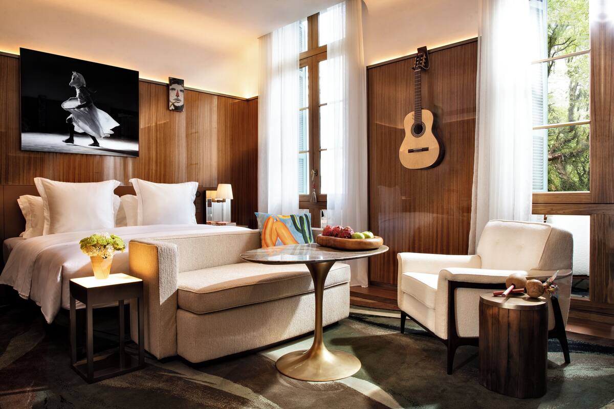 Ein Hotelzimmer mit einem Bett, einer Couch, einem runden Tisch und einer Gitarre an der Wand.