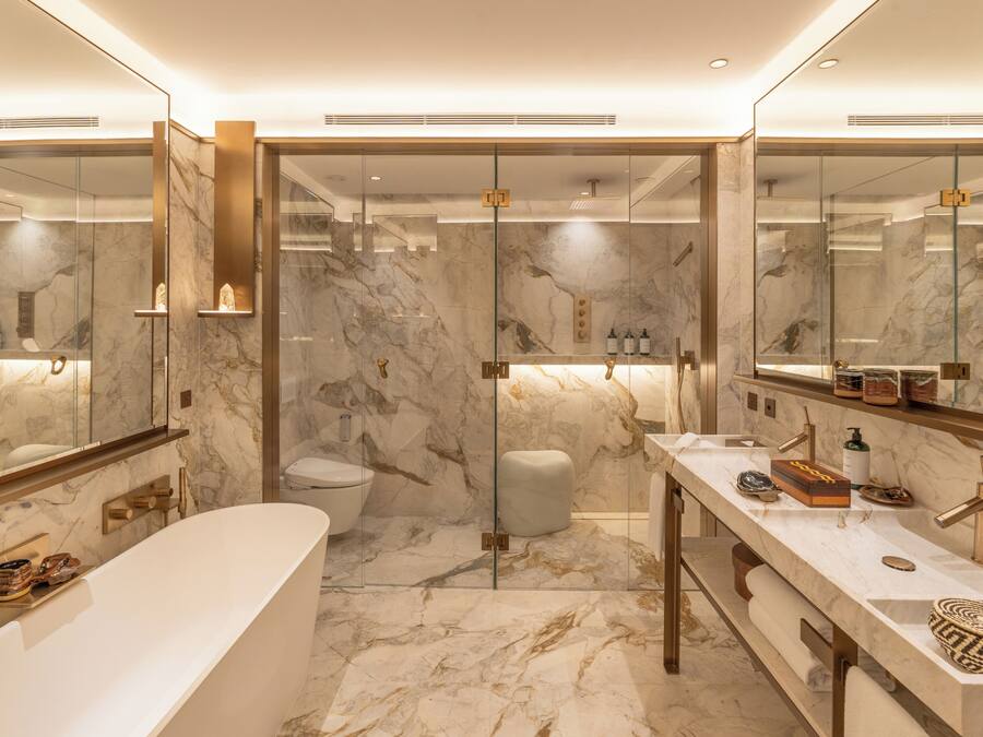 A modern bathroom with a marble floor, a freestanding bathtub, a glass-enclosed shower, and a vanity with a mirror.