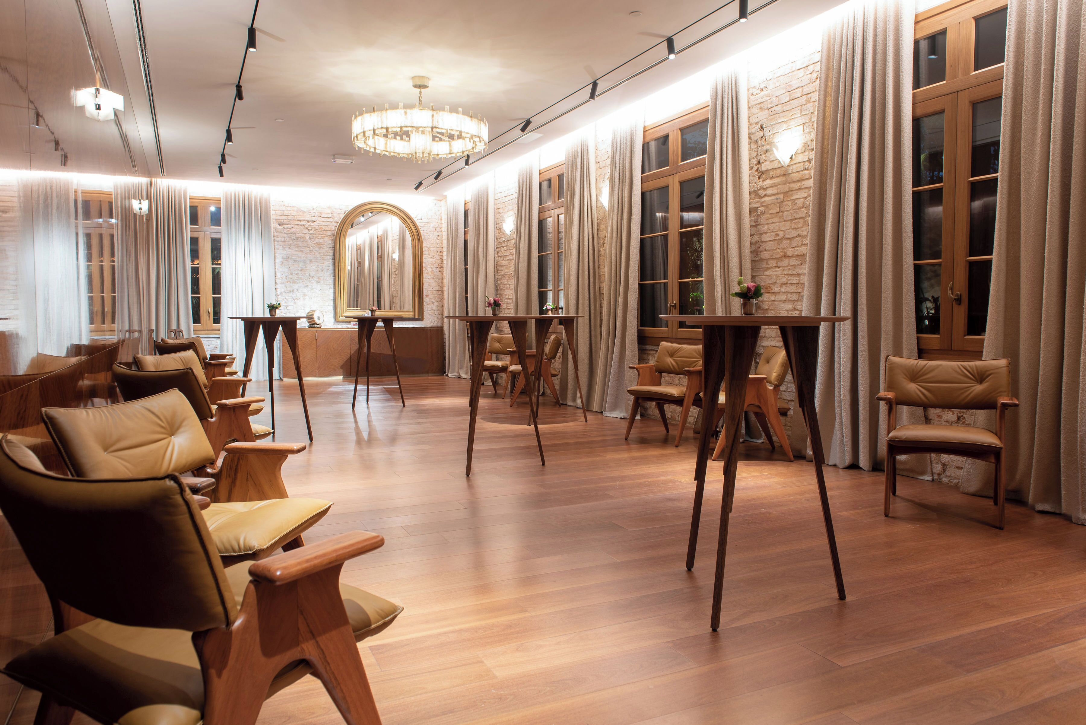A room with wooden flooring, leather chairs, a wooden table, and a mirror.