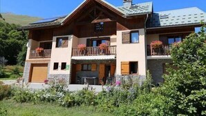 Une maison à deux étages avec un balcon, une cheminée et une façade en pierre.
