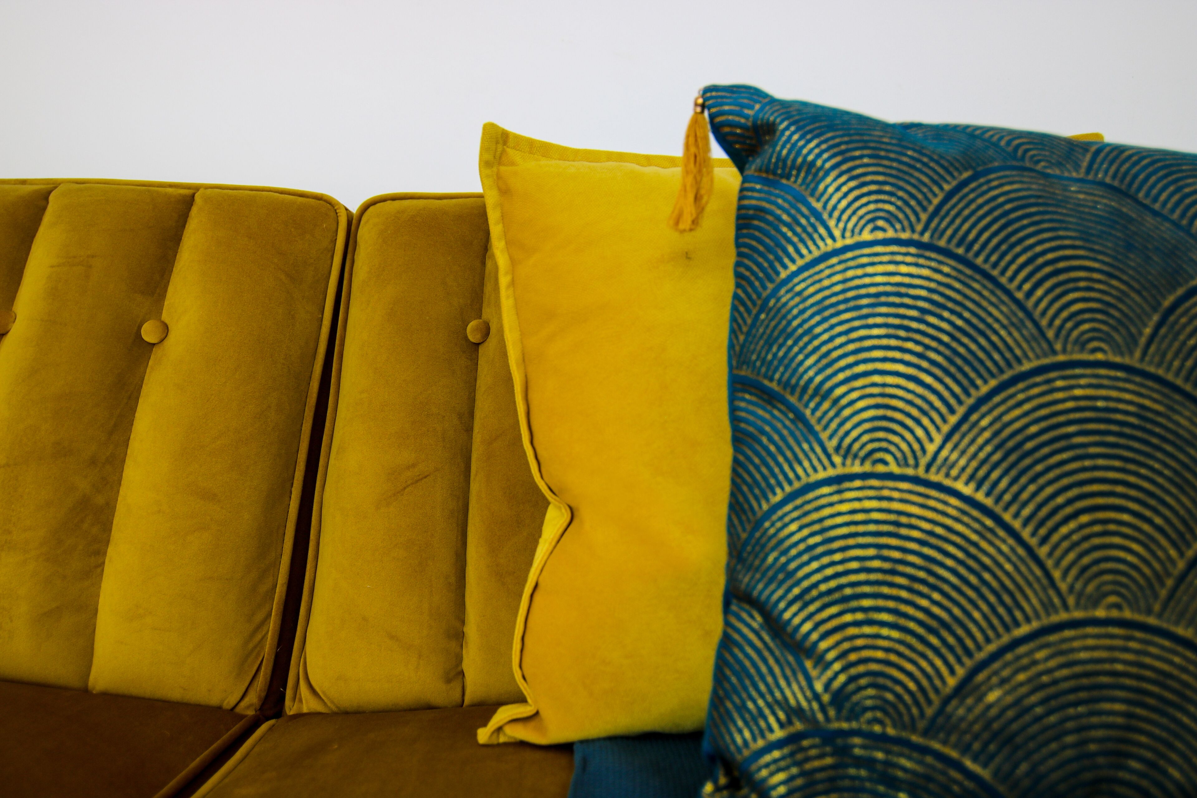 A sofa with a patterned throw blanket and a yellow pillow.