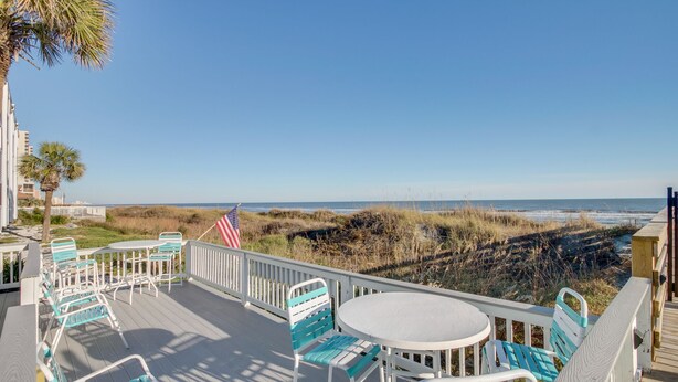 Eine Terrasse mit Sitzgelegenheit und Blick auf den Strand.