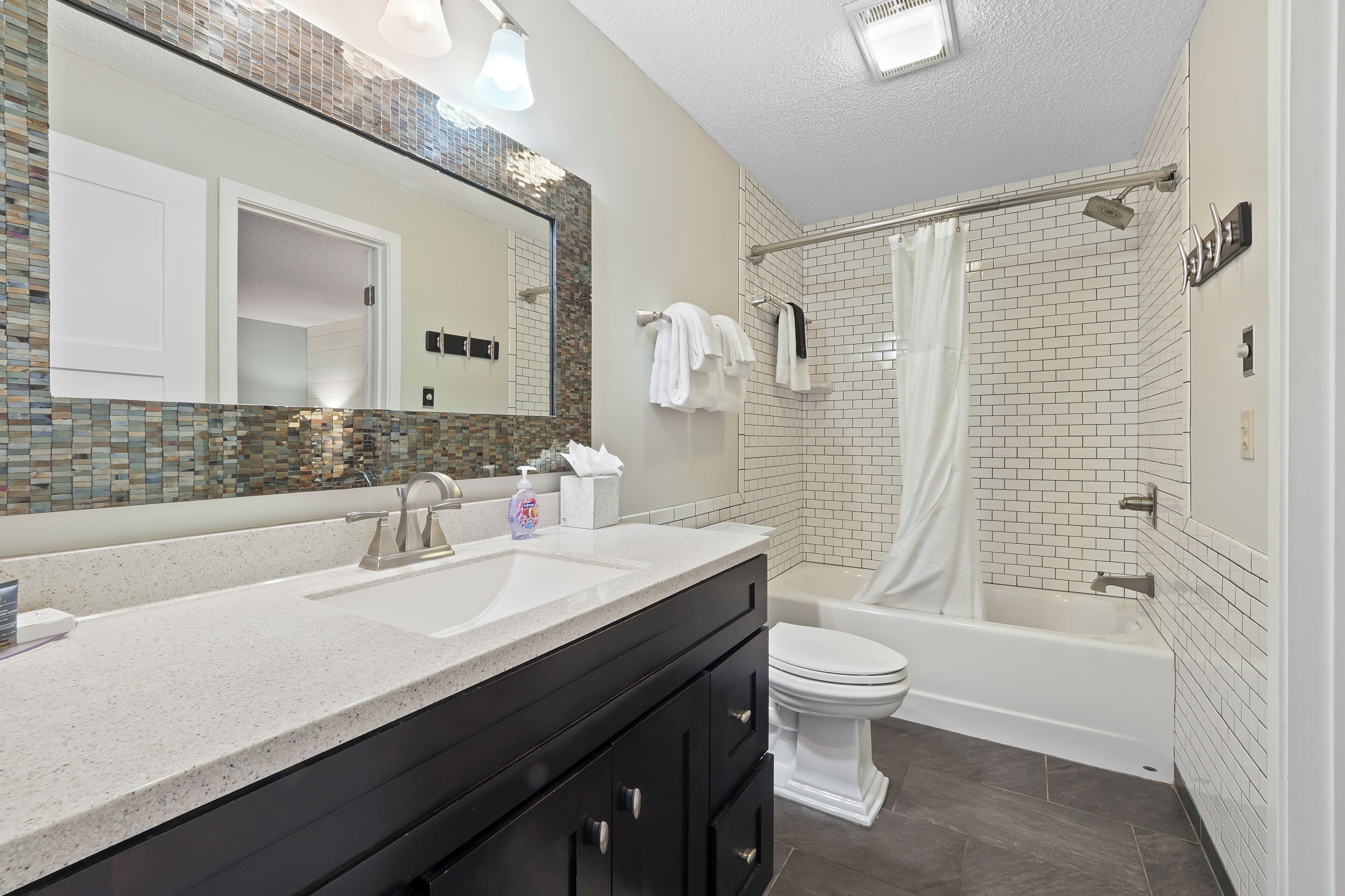 Un baño moderno con un espejo grande, un lavabo, un inodoro y una bañera.