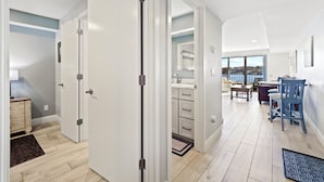 A modern interior with a wooden floor, white walls, and a dining area with blue chairs. - 233 Edgewater | Waterfront View | Pool, Hot Tub, Sauna | Sleeps 4 (Charlevoix)