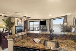 A modern kitchen with a marble countertop, a built-in sink, and a view of the water. - 234 Edgewater | Lake Charlevoix | Downtown Charlevoix | Pool, Hot Tub, Sauna (Charlevoix)