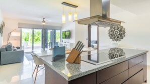 Une cuisine moderne dotée d’un plan de travail en granit, d’une hotte de cuisson en acier inoxydable et de luminaires suspendus.