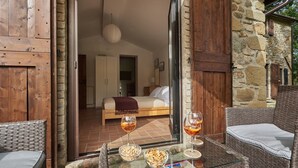 Une chambre à coucher avec un lit, une table de chevet et un luminaire suspendu. Sur une table, on trouve deux verres à vin et quelques collations.