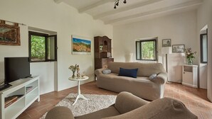 Un salon avec un canapé, un téléviseur et une petite table sur laquelle se trouvent un vase et des verres à vin.