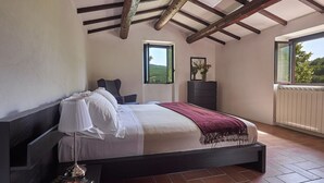 Une chambre à coucher comprenant un lit, une chaise, une commode et une fenêtre donnant sur un paysage verdoyant.
