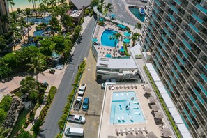 Un hotel con múltiples piscinas, zona de estacionamiento y vistas a la playa.