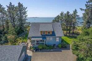 A two-story house with a sloped roof, a front porch, and a small garden area. - AMAZING VIEW, Waterfront, HOT TUB, Pets OK, Enclosed Yard (Bliss) (Chinook)