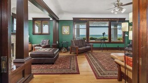 Ein geräumiges Wohnzimmer mit großem Fenster, Deckenventilator und Meerblick.