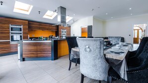 Une cuisine moderne dotée d’appareils électroménagers intégrés, un coin repas avec une table pour quatre personnes et un grand îlot central avec un évier.