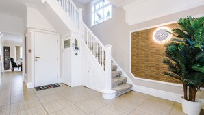 Un hall d’entrée spacieux avec un escalier, un mur décoratif en bois et une plante en pot.
