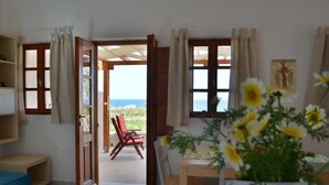 Une pièce avec vue sur la mer, un coin repas avec une table et des chaises, et un canapé bleu.