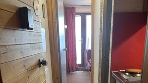 A narrow hallway with wooden paneling on the left, a door with a number plate, and a red wall on the right. - Cosy studio in Plagne Villages at the foot of the slopes (PLAGNE VILLAGE)