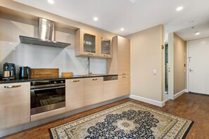A modern kitchen with built-in appliances, wooden cabinetry, and a patterned rug.